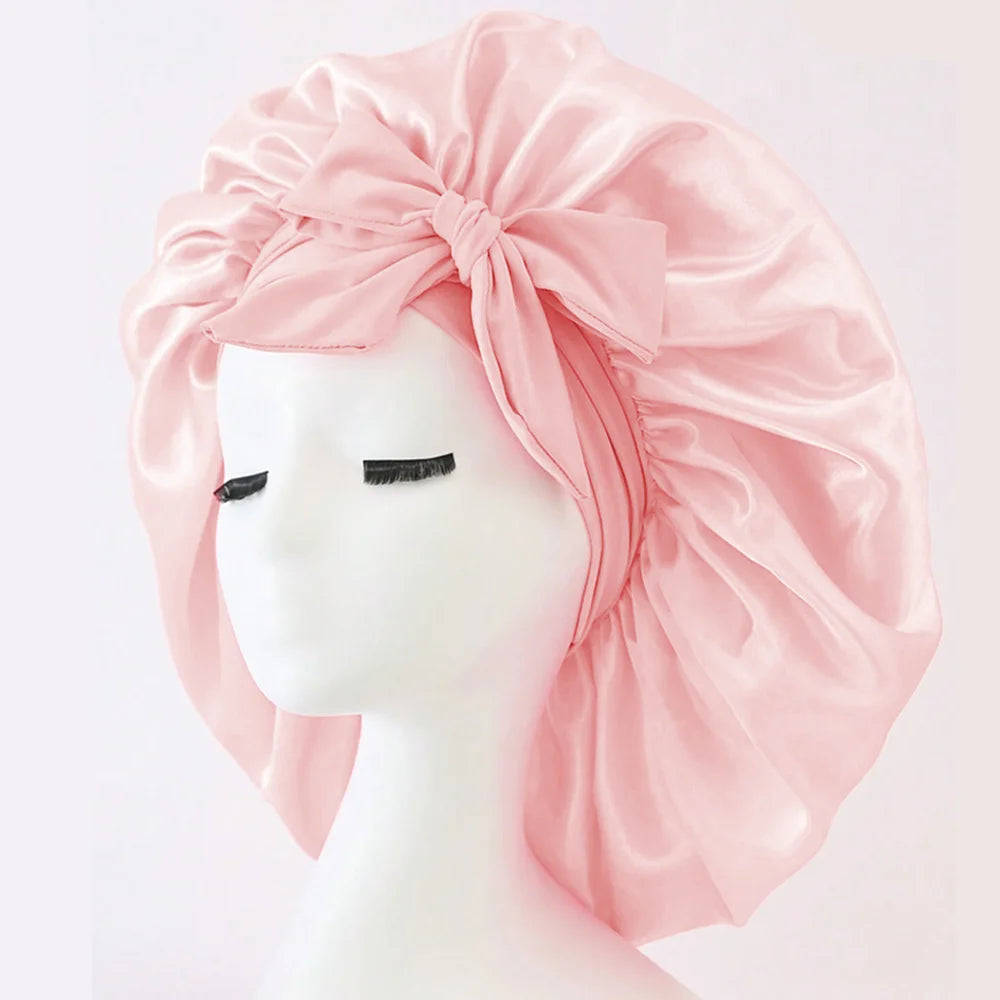 Rosa Seiden-Haube aus Satin, zu einer Schleife gebunden, auf einem weißen Kopfmodell.