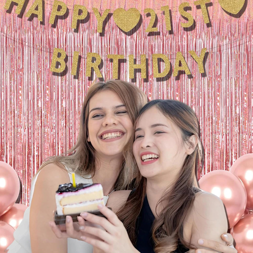 Two young women smiling in front of a pink glitter tinsel curtain backdrop for a birthday celebration