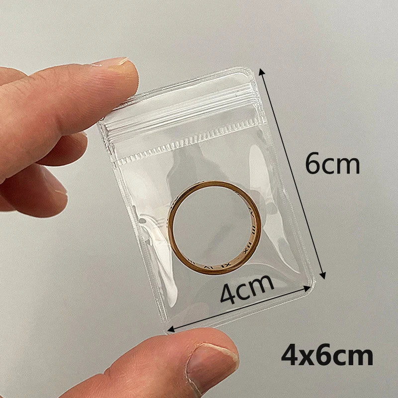 A hand holds a clear PVC zip lock jewelry pouch with a circular opening, measuring 6cm by 4cm.