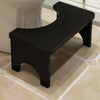 A black portable bamboo toilet squat stool is shown on a light carpet.
