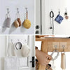 A collection of self-adhesive rotating wall hooks in various colors and materials displayed on a white wall.
