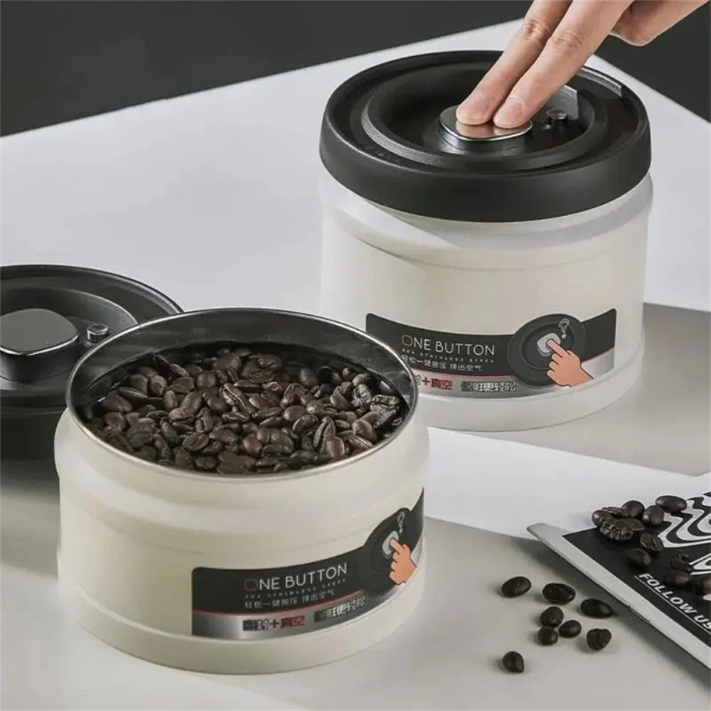 A hand is opening a white stainless steel vacuum sealed storage canister, revealing dark coffee beans inside.