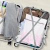 A silver laundry bag with a mesh insert is shown inside a gray rolling suitcase.