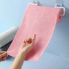 A hand is pulling a pink microfiber tear-off cleaning cloth roll from a hanger against a light blue background.