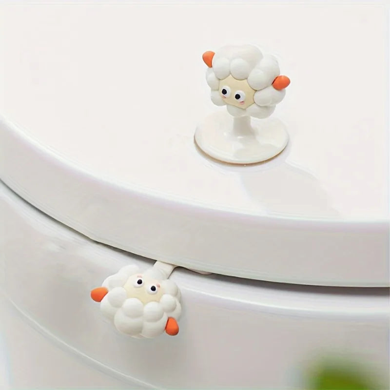 A white cartoon toilet seat lifter handle shaped like a fluffy white sheep with orange accents.