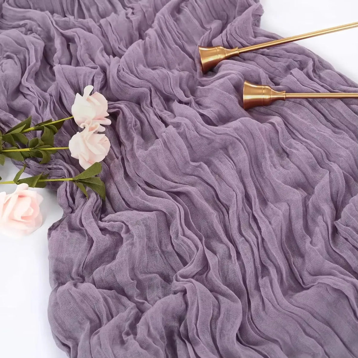 A purple cheesecloth table runner set featuring ruffled fabric and brass-colored spoons.
