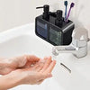 A hand is dispensing soap from a black 3-in-1 kitchen soap dispenser set onto a white surface.