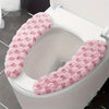 A pink, fluffy washable toilet seat cushion cover is shown inside a white toilet bowl.