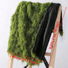 A dark green artificial moss garland draped over a wooden chair, showing its texture and size.