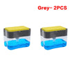 Two grey portable press-type liquid soap dispensers, one filled with blue liquid and the other with yellow liquid.