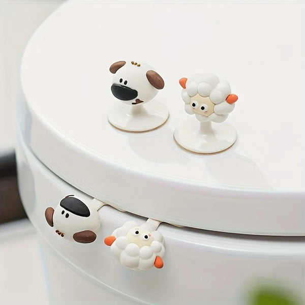 A white toilet seat with decorative lifter handles shaped like cartoon sheep and cows.