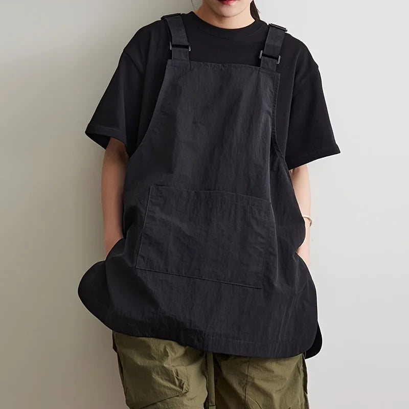 A person wearing a black waterproof outdoor work apron over a black t-shirt and olive green pants.