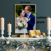 A framed custom photo print of a couple kissing, displayed on a mantel with candles and greenery.