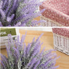 A close-up of artificial lavender flowers in purple and gray arranged in a woven basket.