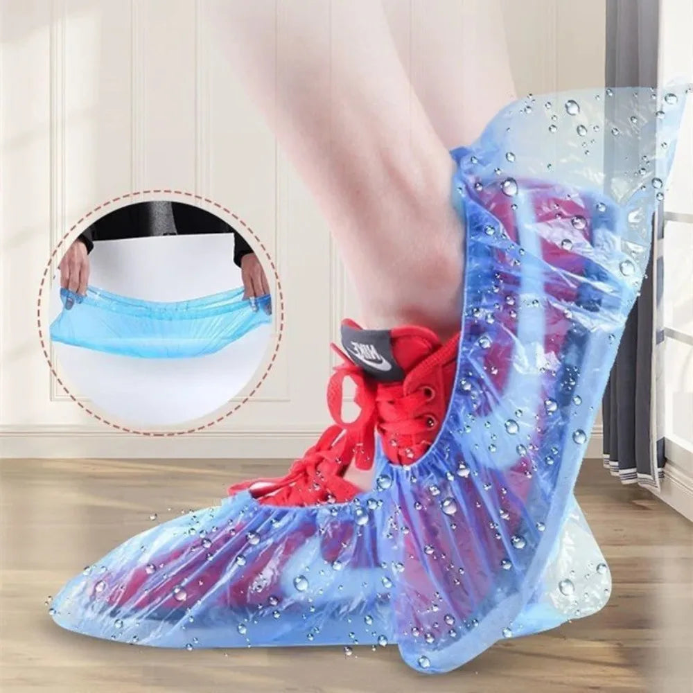 A person's foot is wearing clear plastic shoe covers with water droplets on a wooden floor.