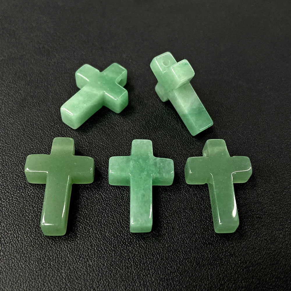 Four light green natural agate and jasper cross pendant charms arranged in a semi-circle on a dark surface.