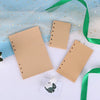 A set of blank kraft paper notebook refills with gold star accents and a green ribbon on a white background.