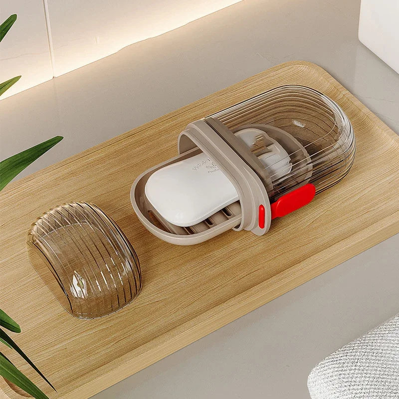 Une boîte de savon de voyage portable avec un couvercle transparent et une barre de savon blanche est présentée sur un platea