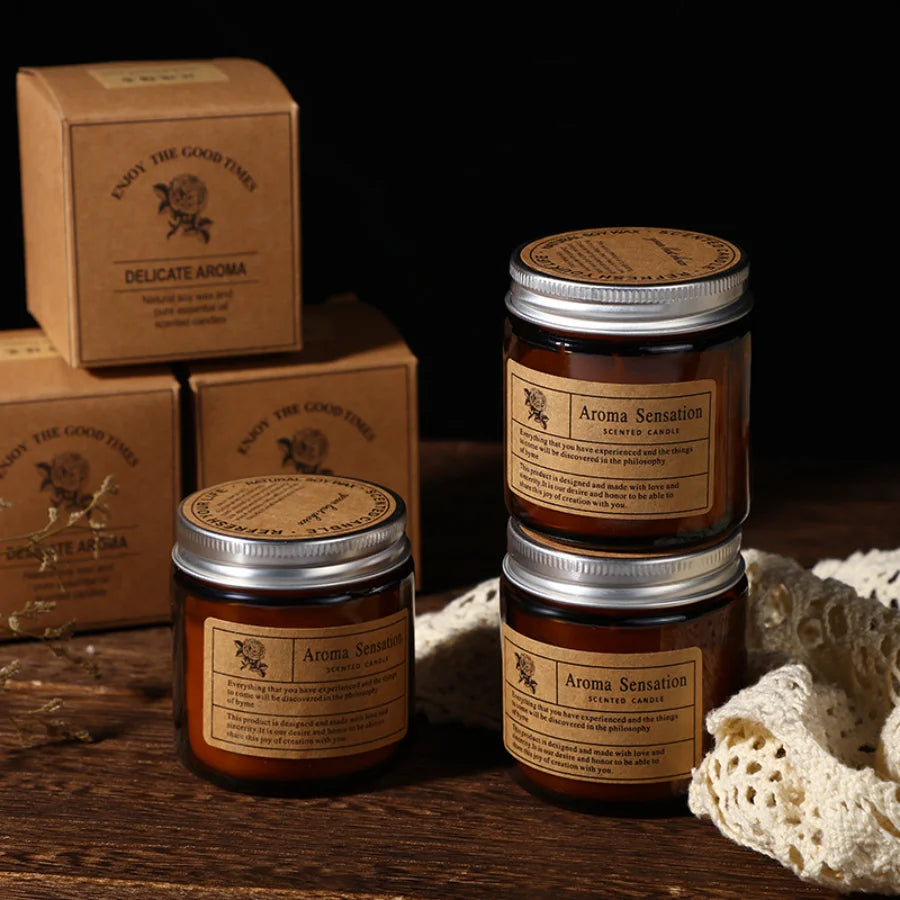 Three jars of Aroma Sensation scented candles in brown glass cups are displayed on a wooden surface.