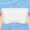 Hands holding a white, textured facial cleansing towel against a light blue water background.