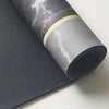 Roll of dark gray diatomite bath mat with a gold accent ring