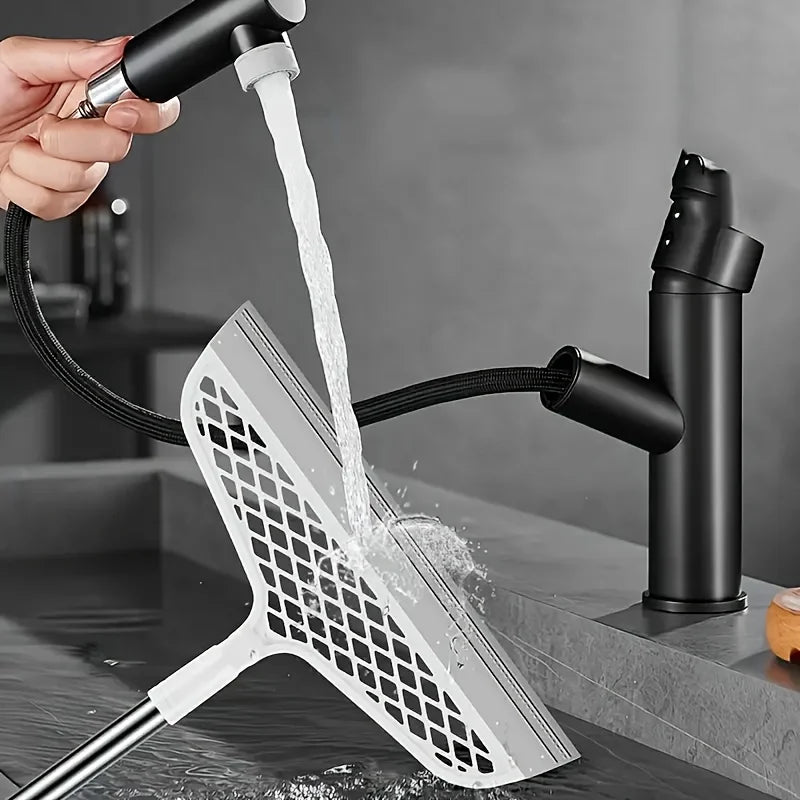 A hand is using an ergonomic detachable magic broom and scraper set to clean a surface.