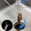 A close-up of a four-claw hand grip tool used to remove stuck food from a sink drain.