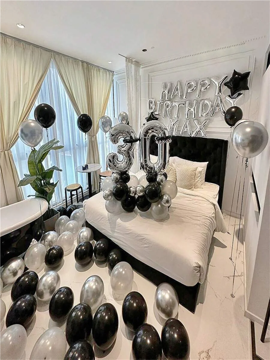 Dormitorio decorado para una fiesta de cumpleaños con globos plateados y negros y un globo de número de papel metálico grande
