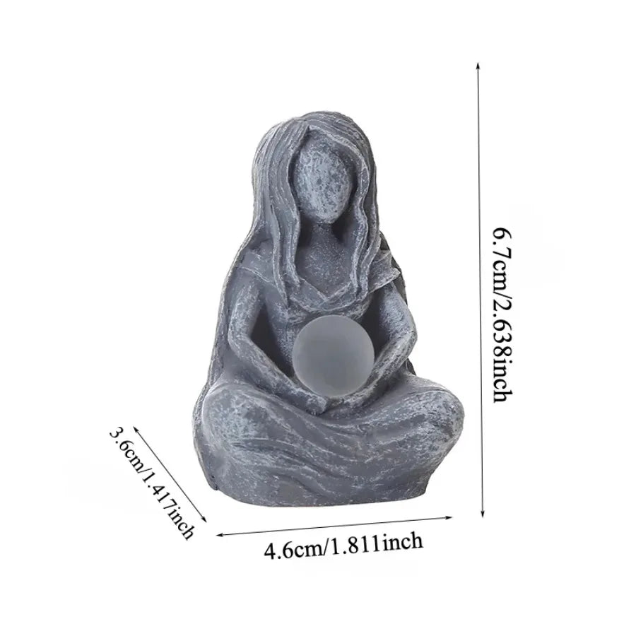A gray resin statue of a female figure with long hair sitting in a meditative pose.