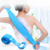 A woman is using a long blue silicone body scrubber with a detachable loofah on her back.