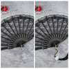 A black lace fabric folding hand fan with a decorative edge shown against a gray background.