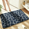A dark blue pebble embossed bathroom rug placed on a light wooden floor.