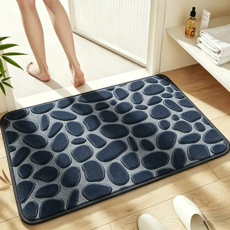 A dark blue pebble embossed bathroom rug placed on a light wooden floor.