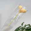 Un bouquet de fleurs de carnation en coton jaune fait main, présenté dans une gaine en plastique transparent.