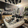 Guirnalda de globos plateados y negros con el número tres decorando una cama para una celebración de cumpleaños.