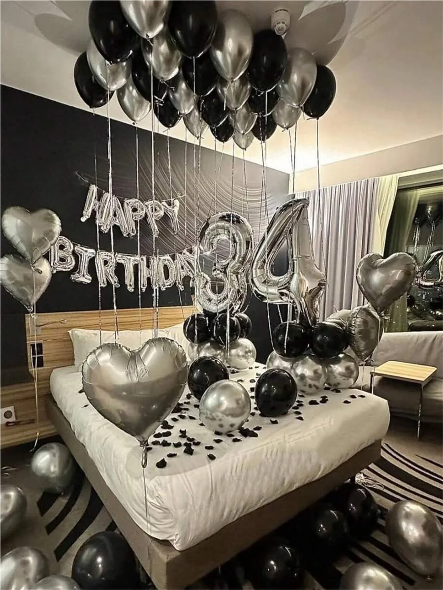 Guirnalda de globos plateados y negros con el número tres decorando una cama para una celebración de cumpleaños.