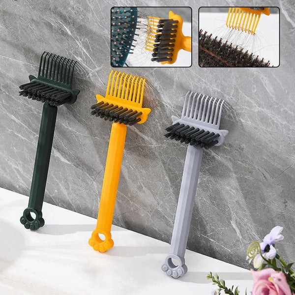 Three hair grooming tools including a black comb, an orange brush, and a gray brush displayed against a gray marble backgroun