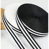 Two black and white grosgrain ribbon rolls are shown, one rolled flat and the other partially unrolled.