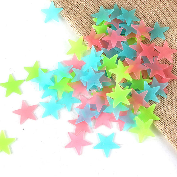 A pile of glow-in-the-dark star wall decals in various shades of pink, blue, and green resting on burlap fabric.