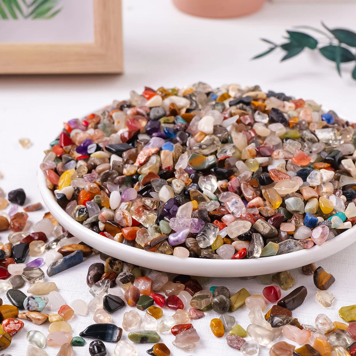 Un tas de gravier et de pierres de cristal naturel aux couleurs et formes variées, éparpillés sur une surface blanche.