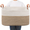 A person is holding a large woven cotton storage basket with light beige and brown striped sections.