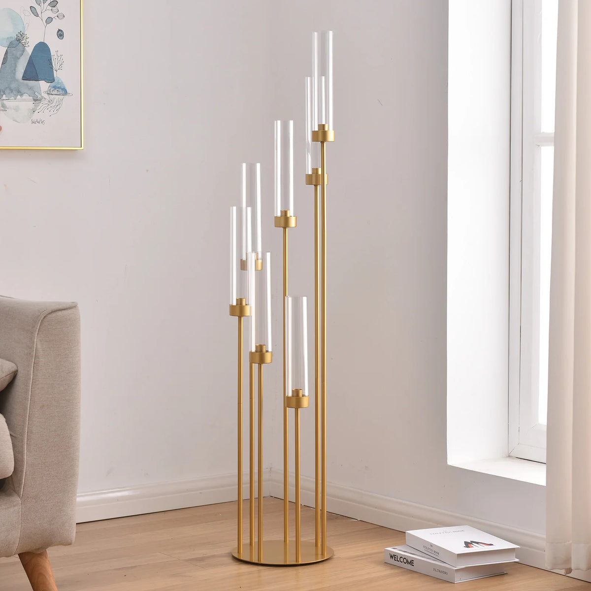Centro de mesa de candelabro de 7 brazos dorado y alto con velas de vidrio transparente en una pared blanca.