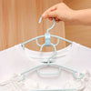A hand is hanging a white shirt on a light blue plastic clothes hanger for wardrobe organization.