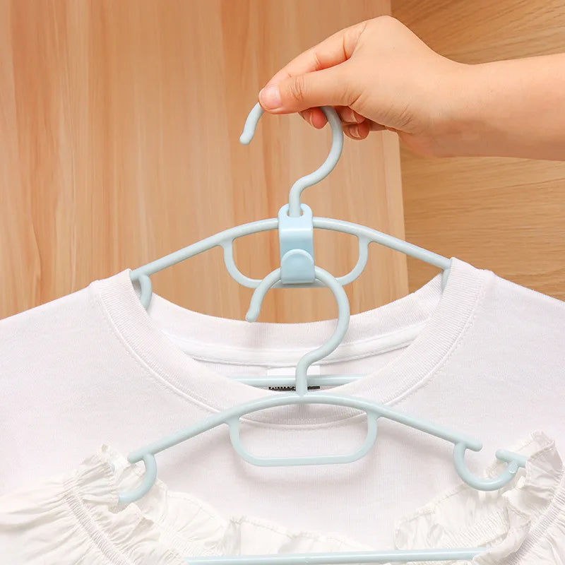 A hand is hanging a white shirt on a light blue plastic clothes hanger for wardrobe organization.