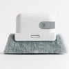 A white window and gap cleaning brush resting on a gray, fibrous cleaning mat.