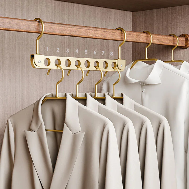 A wooden clothing rack with multiple gold-colored hangers displaying light beige shirts.