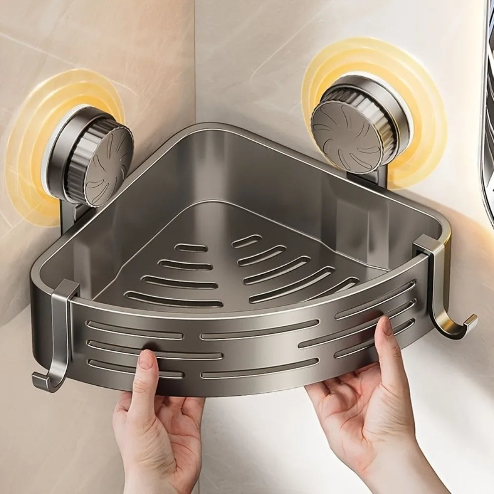 A hand is holding a triangular stainless steel suction cup storage shelf against a light-colored wall.