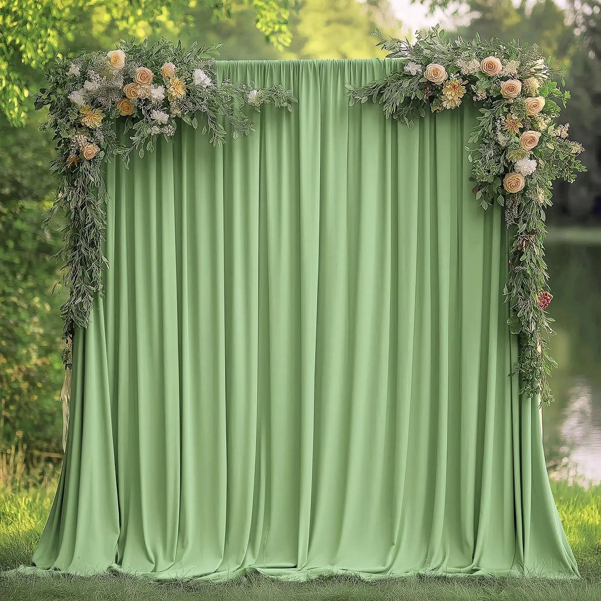 Fondo de tela verde salvia suave con cortina drapeada y arreglo floral de vegetación.