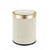 A cylindrical trash can with a gold rim and off-white ribbed body.
