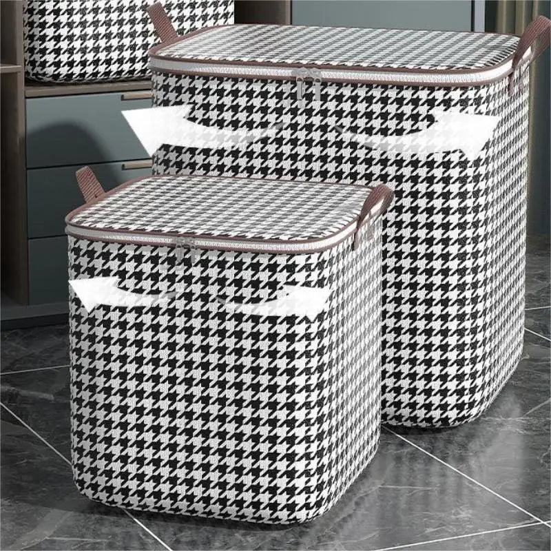 Un couple de sacs de rangement pour vêtements pliables, à motifs noir et blanc à carreaux, posés sur une surface sombre.